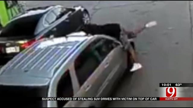 Suspect Accused Of Stealing SUV Drives With Victim On Top Of Car